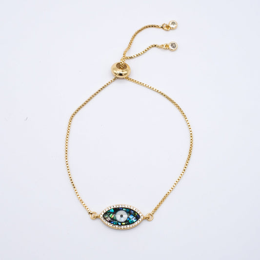 Gold adjustable bracelet with an evil eye charm on a white background